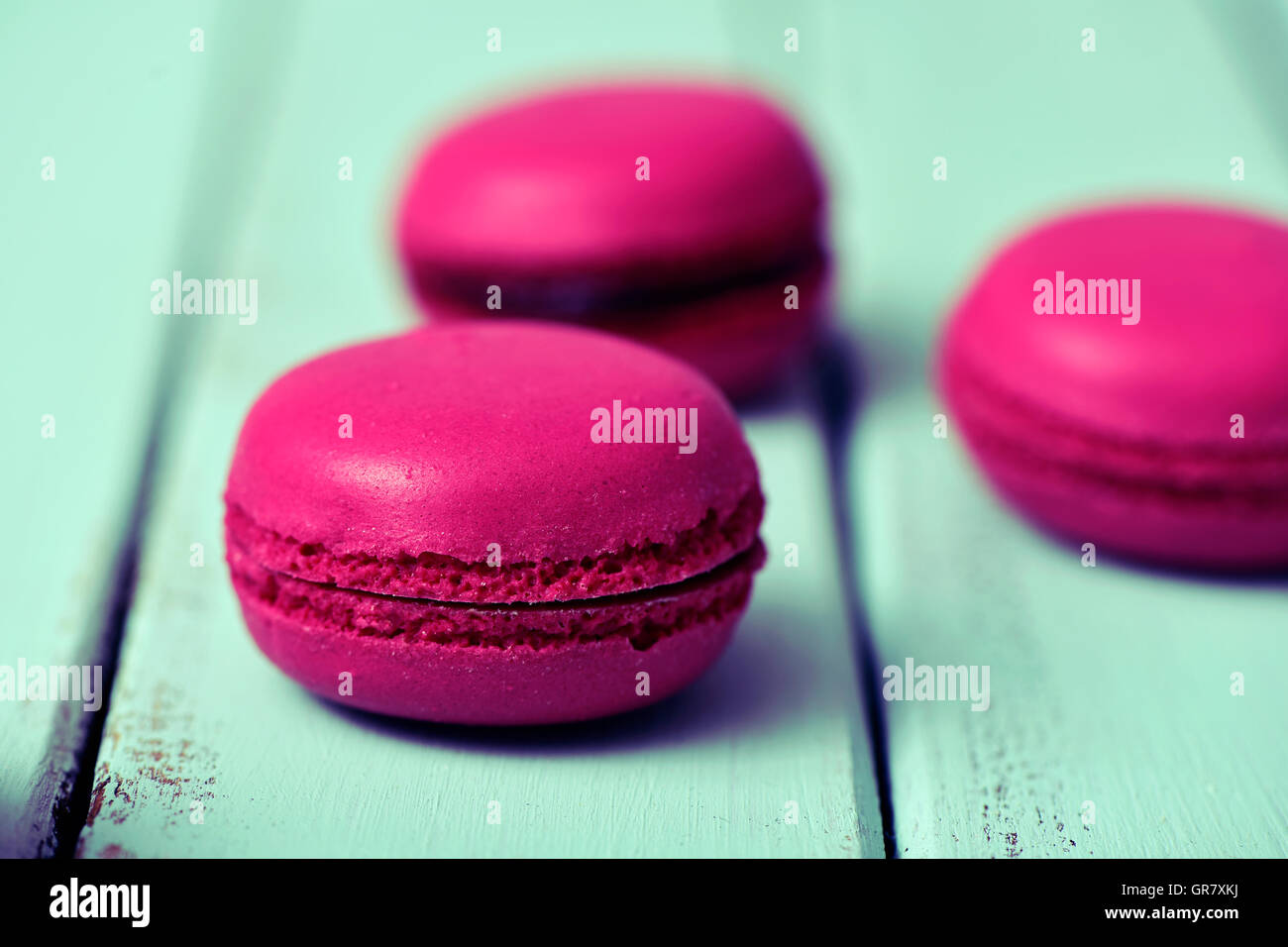 Primo piano di alcuni appetitosi viola macarons su un blu pallido rustico superficie in legno Foto Stock
