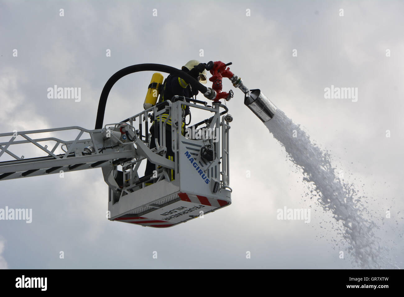 Vigile del fuoco sulla scala per combattere il fuoco Foto Stock