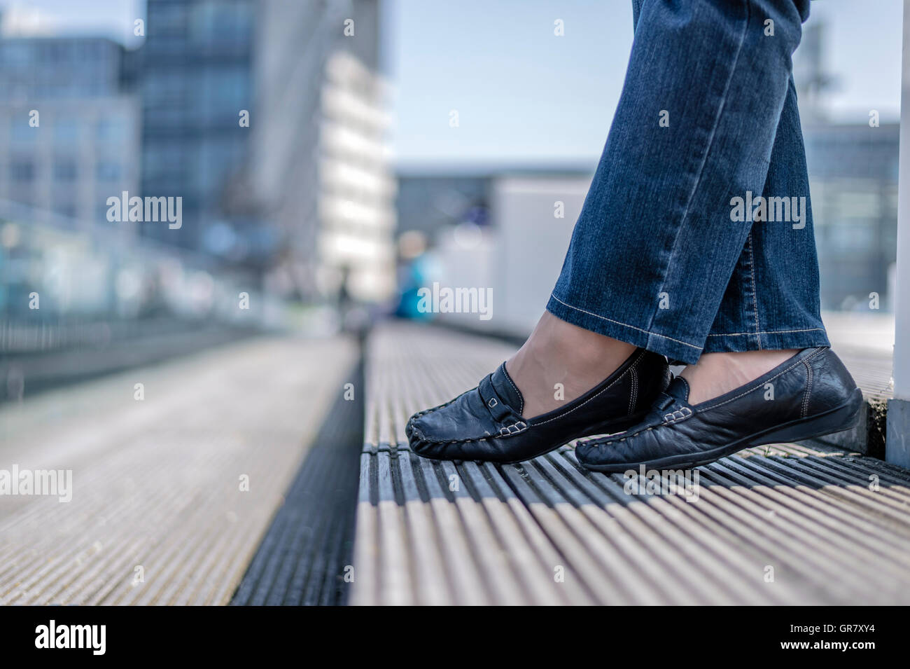 Gambe e piedi di una giovane donna in jeans e scarpe piatte Foto Stock