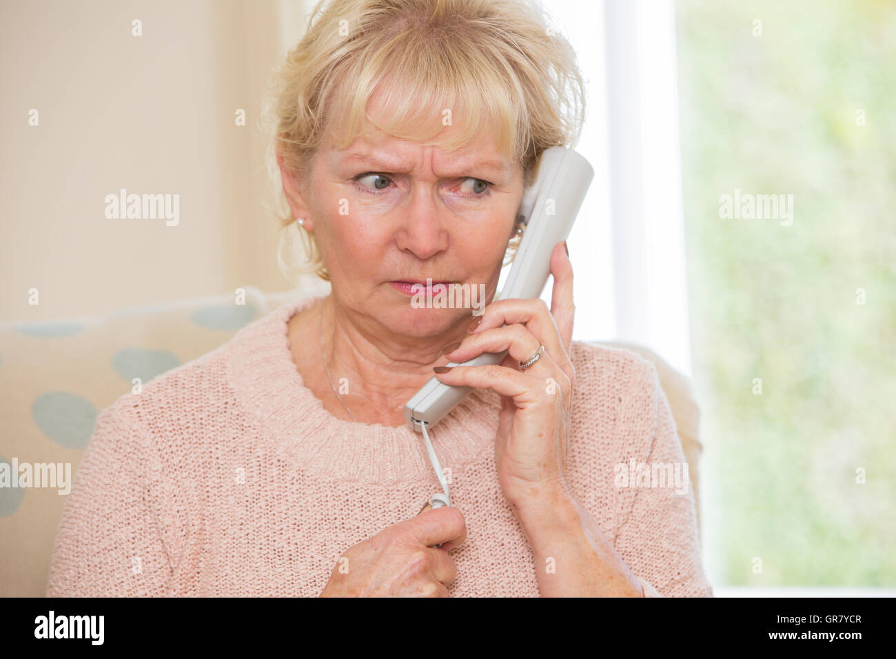 Preoccupato Senior donna rispondendo Telefono in casa Foto Stock
