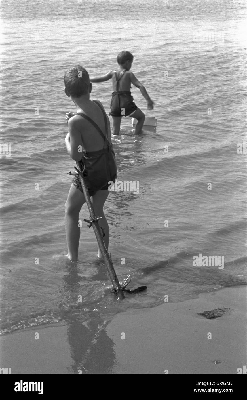 Bambini che giocano nella sabbia 1970 BW Foto Stock