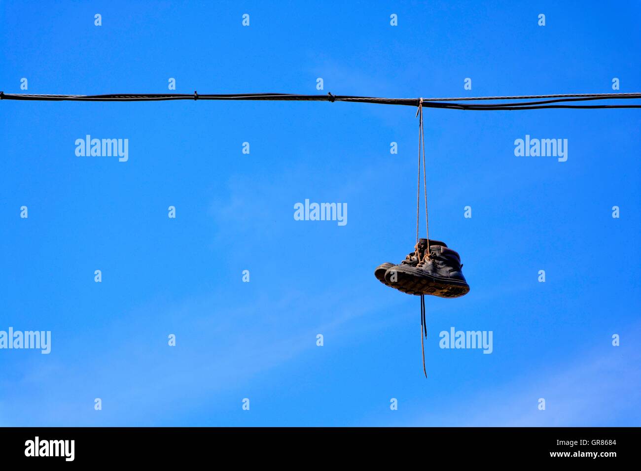 Stivali vecchi appesi su cavi elettrici Foto Stock