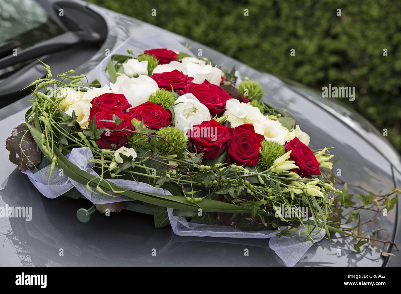Sposa Heart-Shaped auto bouquet di rose bianche e rosse sulla vettura di colore grigio Foto Stock