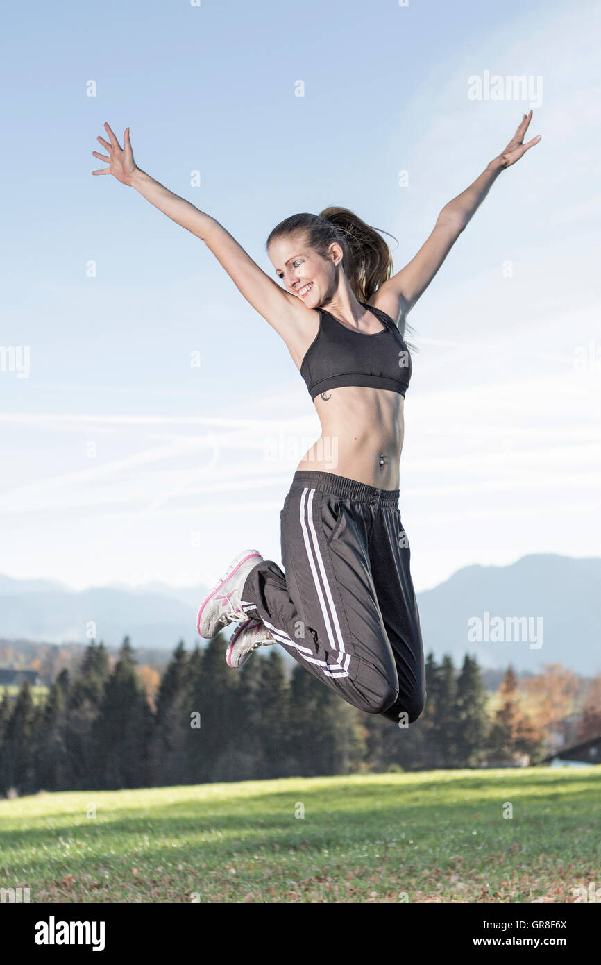 Giovane donna con un abito sportivo salta pieno di vitalità in aria Foto Stock