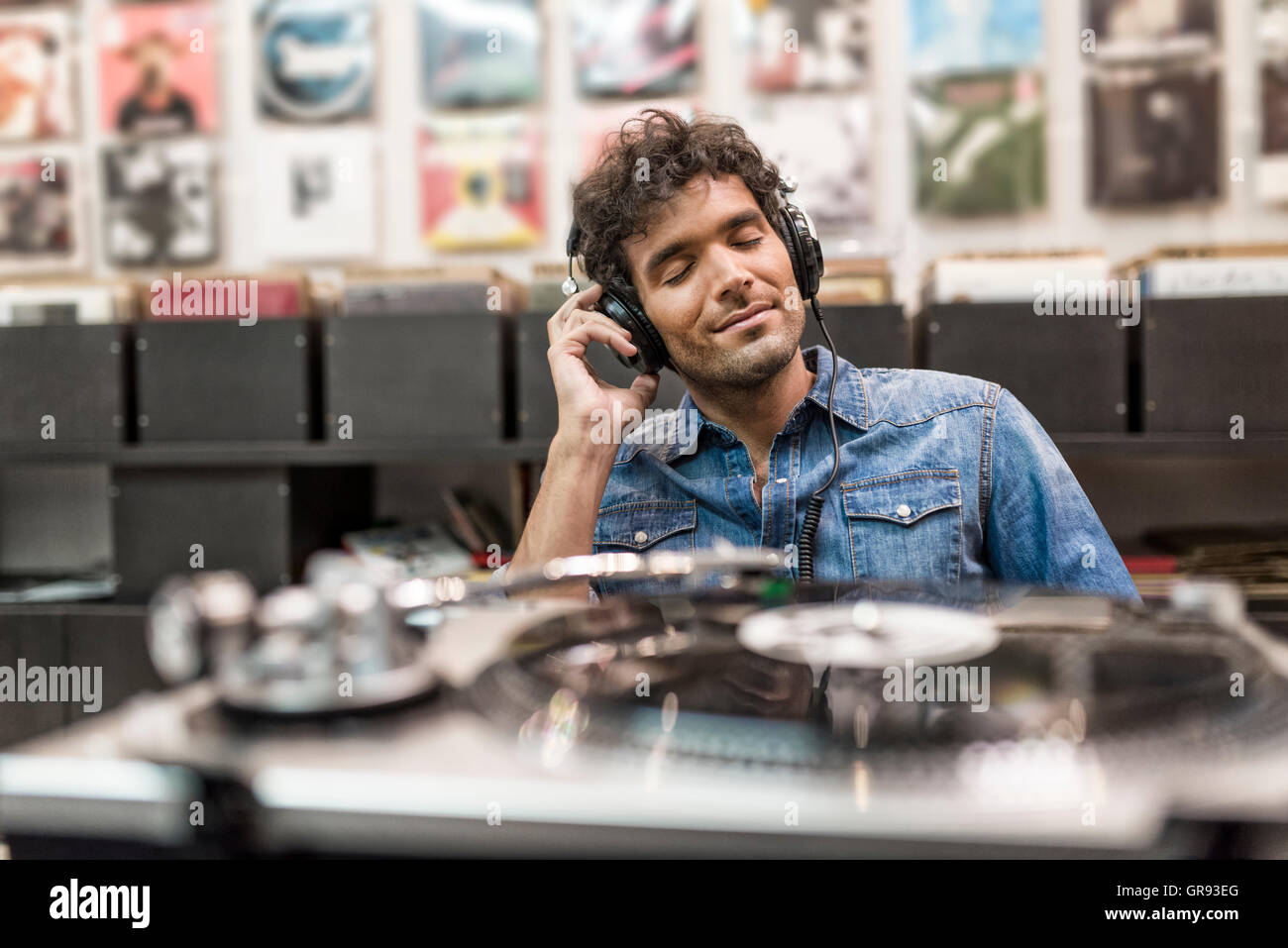 Giovane uomo gli occhi chiusi ascoltando un record nel vinile archivio di record Foto Stock