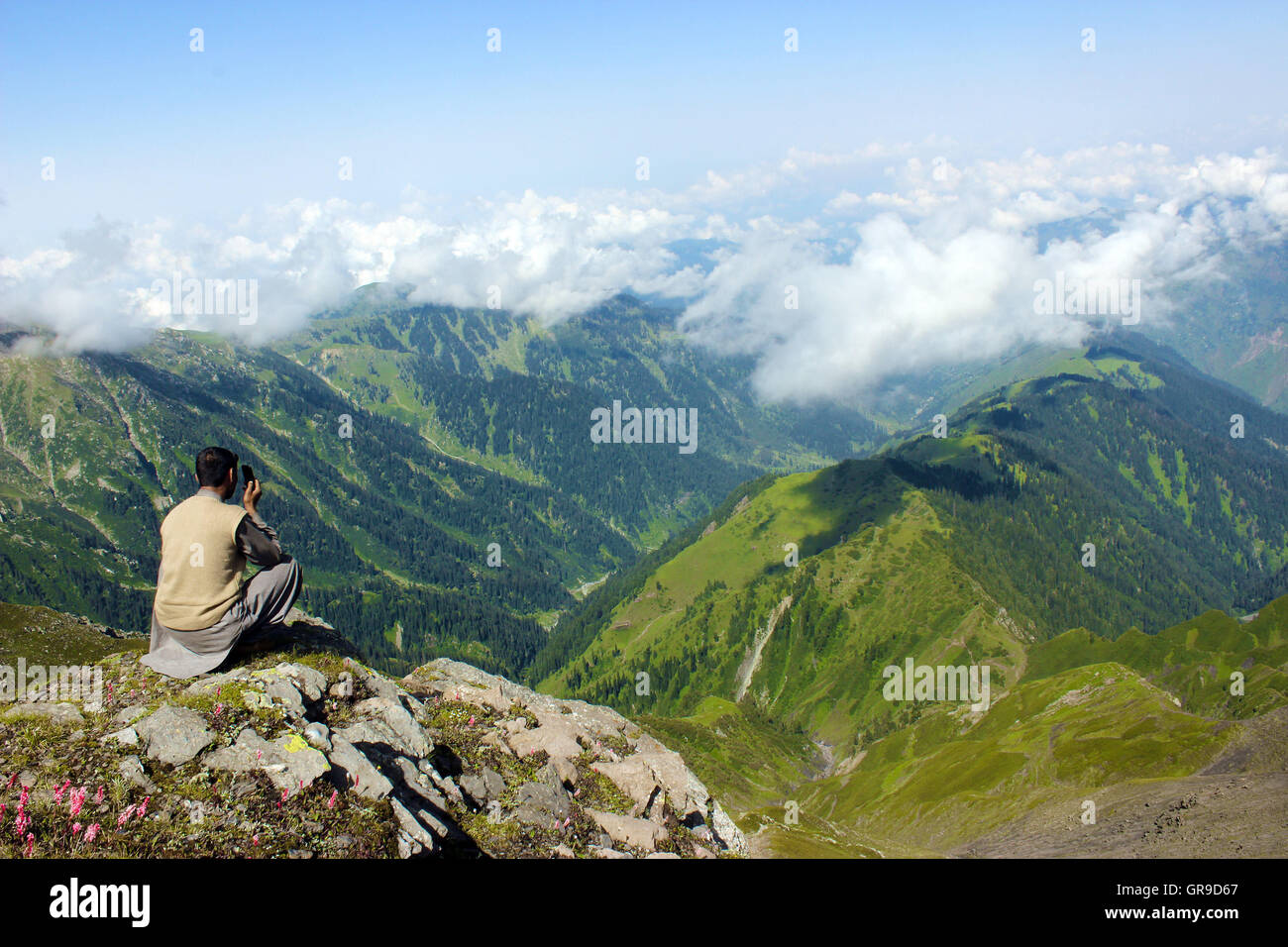 Un uomo che cerca di individuare un gruppo di lavoro di rete mobile nel pir panchal(la montagna più alta gamma di Himalaya inferiore) Foto Stock