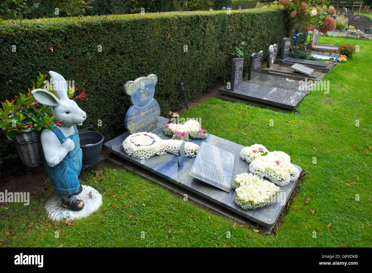 La tomba di un bambino con una statua di un coniglio con fiori in esso Foto Stock