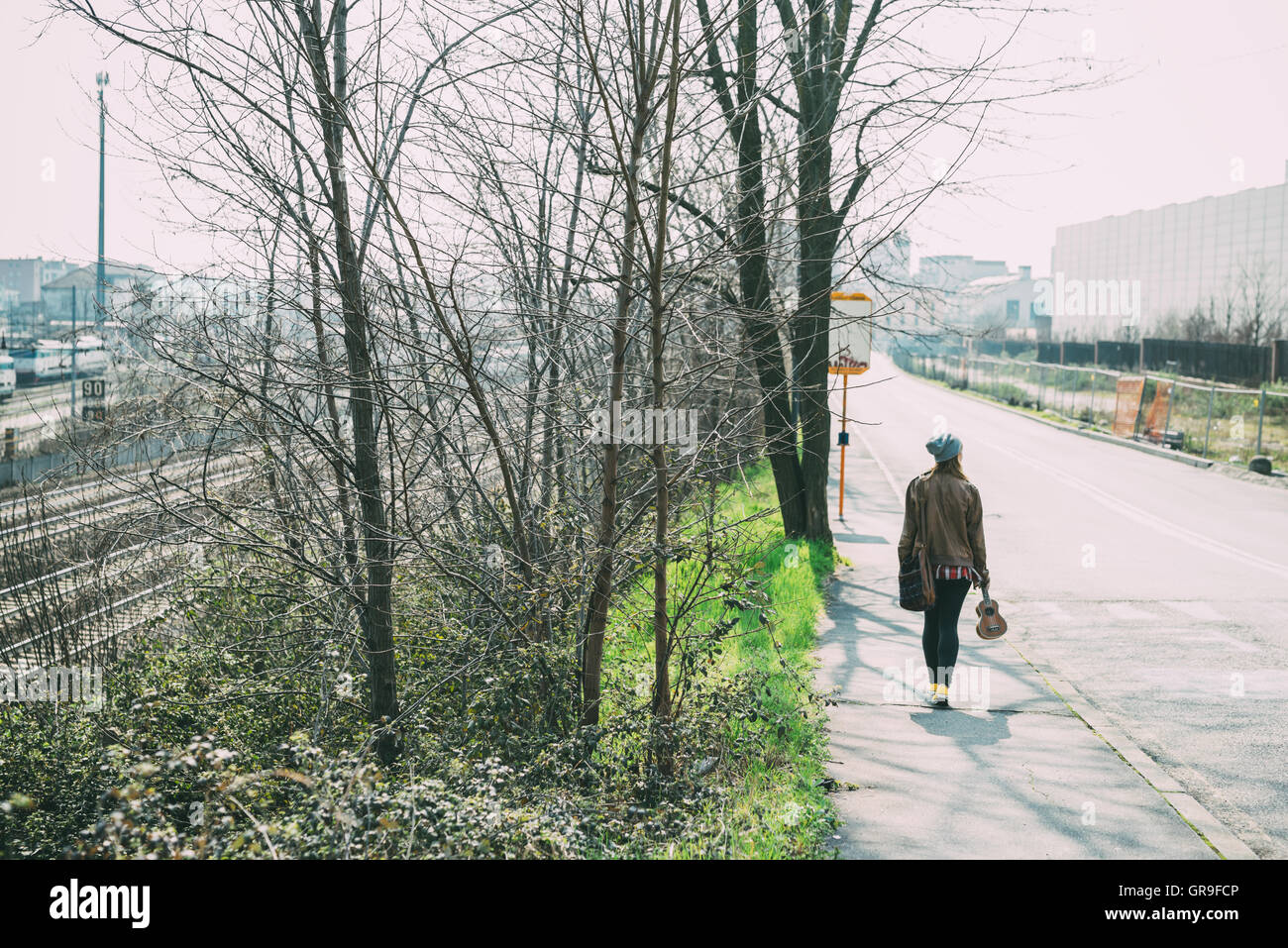 Giovane bella bionda hipster donna passeggiando nella città di tenuta di strada ukulele, affacciato - serenità, musicista, ispirazione c Foto Stock