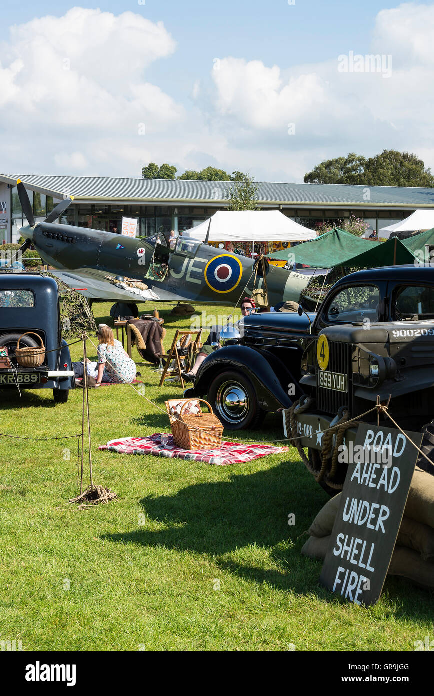 Un RAF Spitfire, una Jeep americana vecchia e auto d'epoca in mostra al circuito di Oulton Park Motor Racing per la Gold Cup Meeting vicino Tarporley Cheshire UK Foto Stock