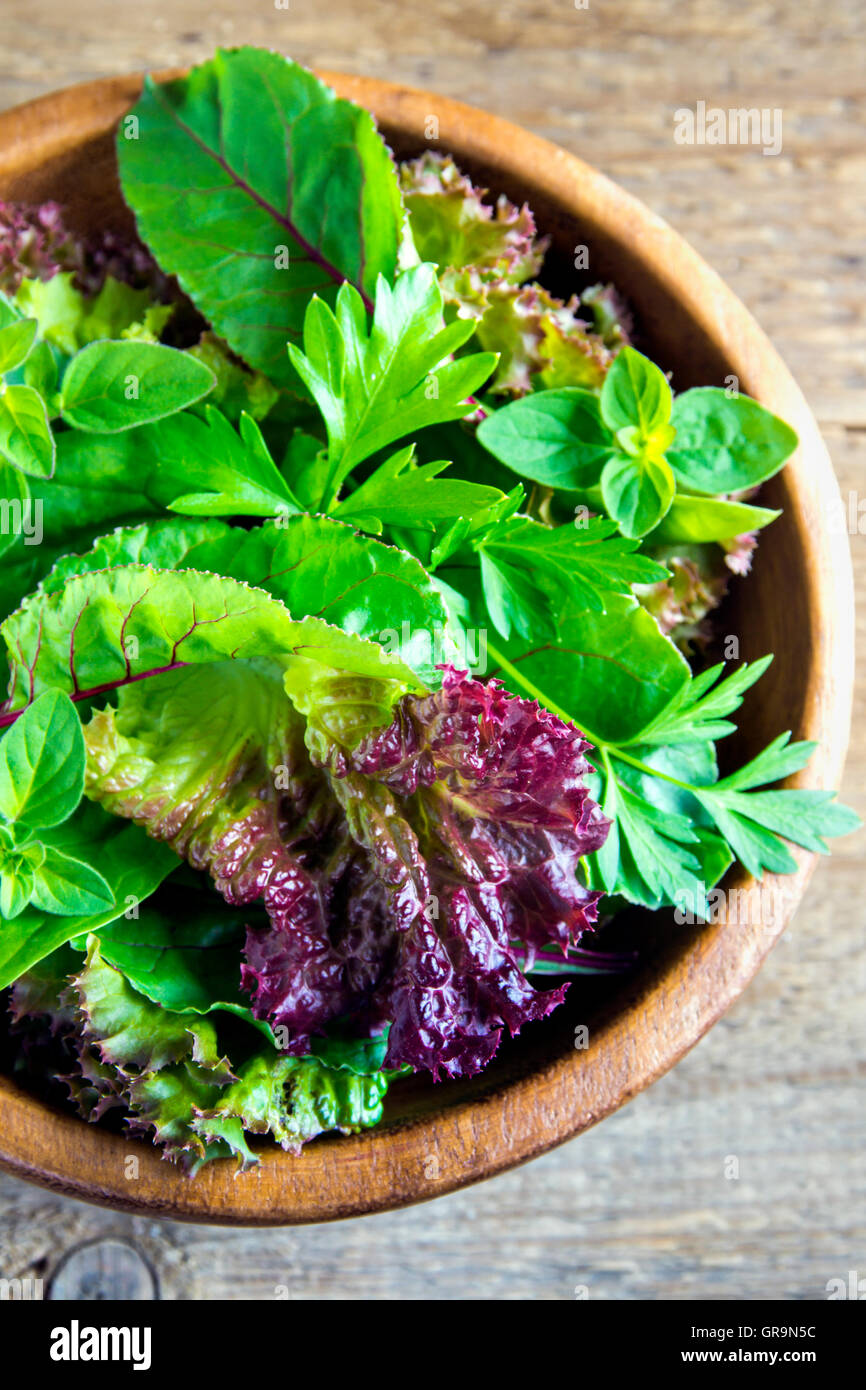 Organico fresco verde insalata mista lascia oltre rustico sfondo di legno Foto Stock