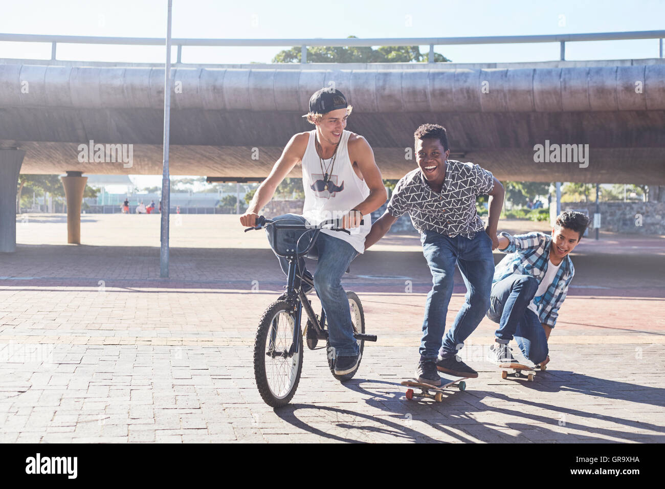 Ragazzi adolescenti equitazione biciclette BMX e skateboard a sunny skate park Foto Stock