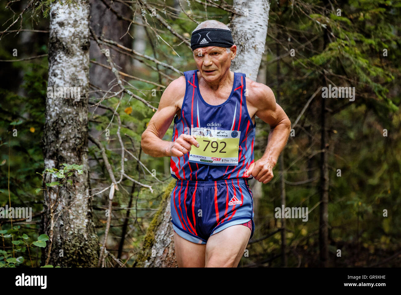 Vecchio maschio sano atleta che corre nel bosco durante la maratona di montagna Foto Stock