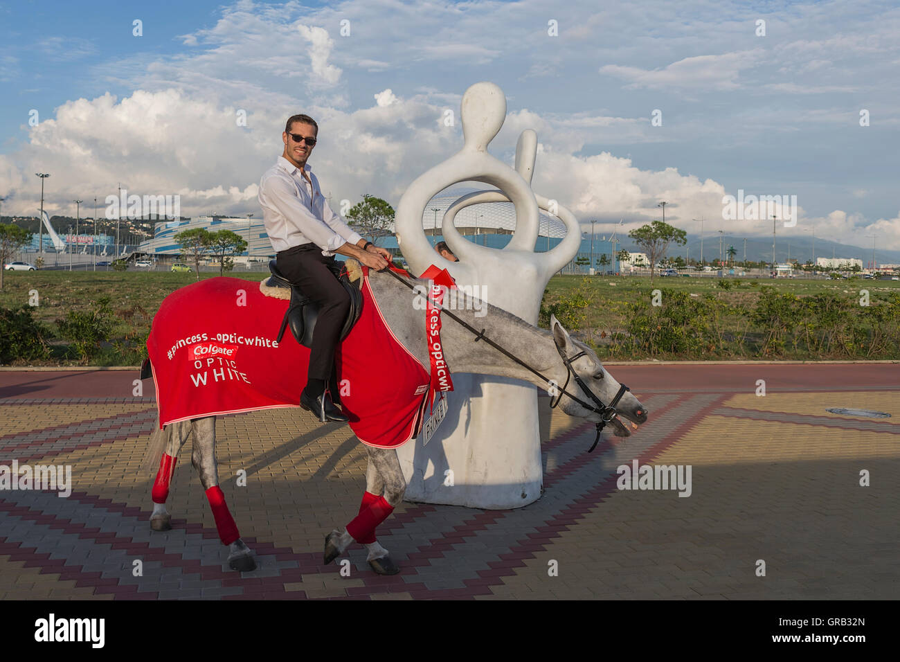 Un uomo su un cavallo grigio in motion, pubblicizza merci, Sochi, il Villaggio Olimpico, Russia Foto Stock