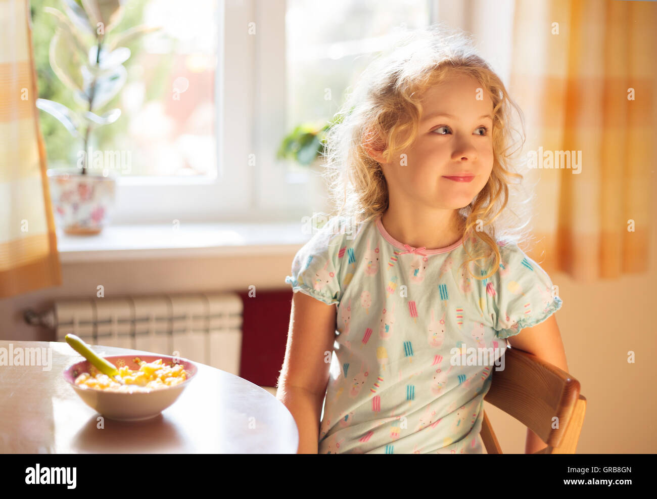 Carino bambina avente la colazione, cereali con latte Foto Stock