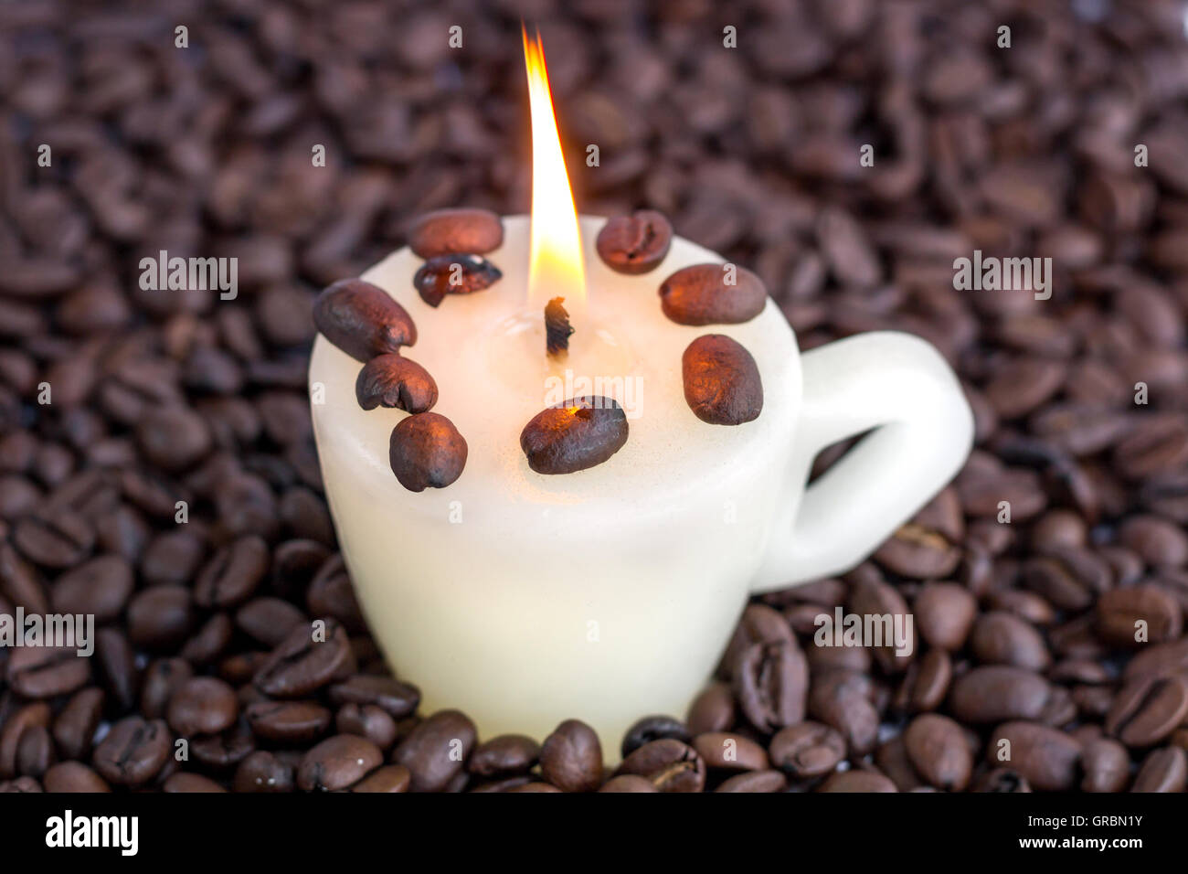 Ancora la vita della candela di coppa con fiamma calda sparsi nel caffè torrefatto in grani Foto Stock