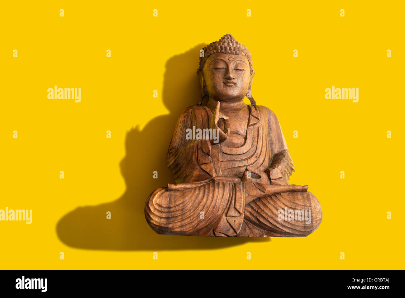 Una figura di Buddha su uno sfondo giallo Foto Stock