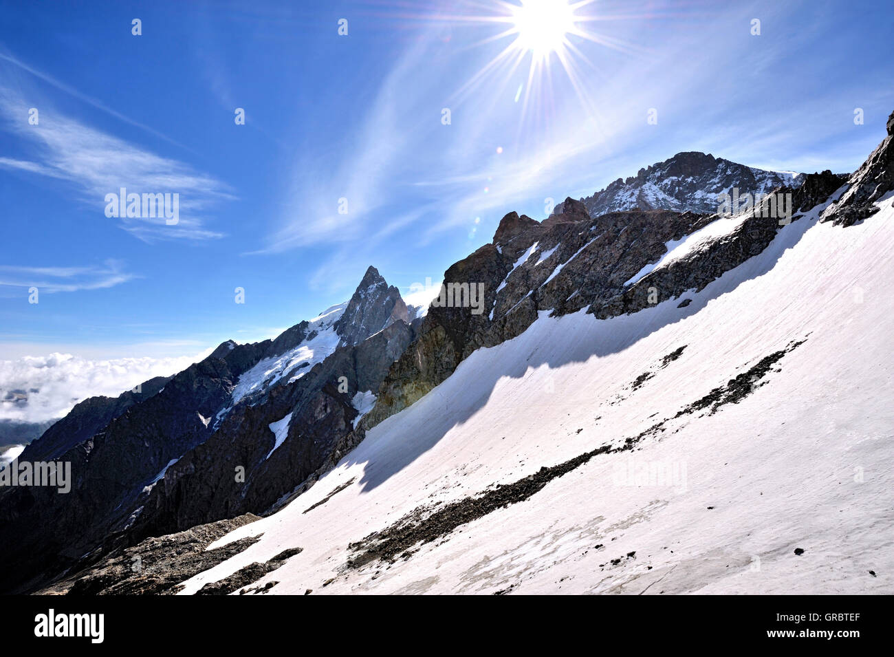 La luce diretta del sole oltre il paesaggio di neve con la cima della montagna di La Meije, La Grave, sulle Alpi francesi, Francia Foto Stock