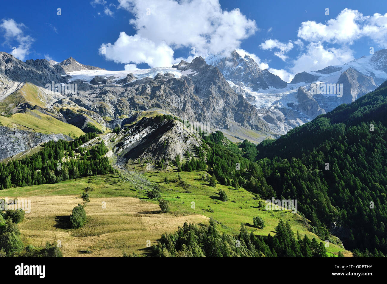 Il paesaggio alpino con il verde delle colline e montagne dalle vette innevate del villaggio La Grave, sulle Alpi francesi, Francia Foto Stock