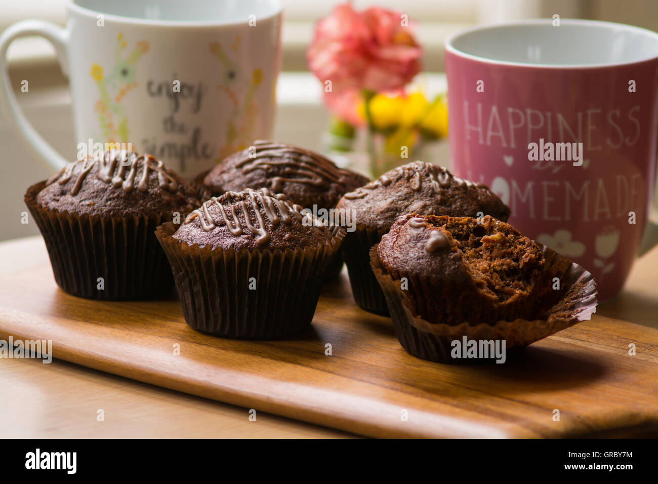 Muffin al cioccolato con tè dalla luce della finestra Foto Stock