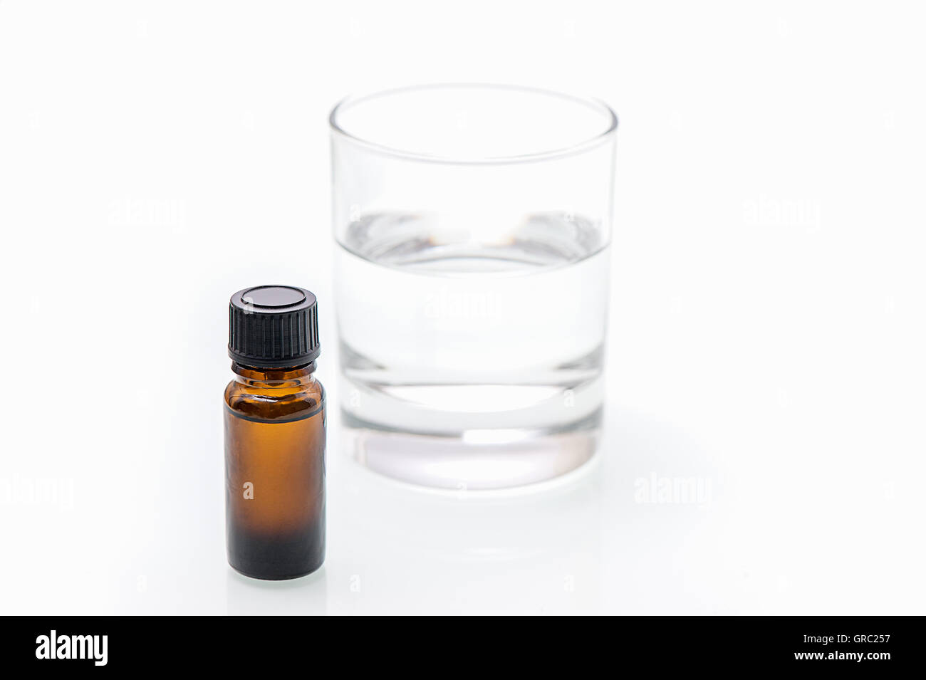 Bottiglia marrone con la medicina su sfondo bianco è accanto è un Waterglas Foto Stock