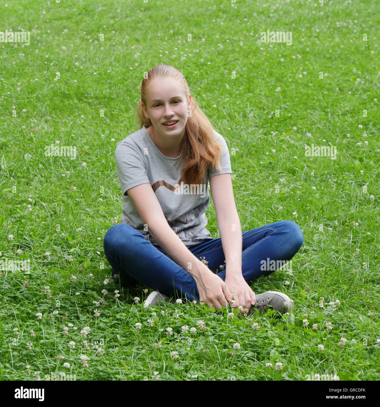 Adolescente, giovane ragazza seduta Cross-Legged su un prato di fiori Foto Stock