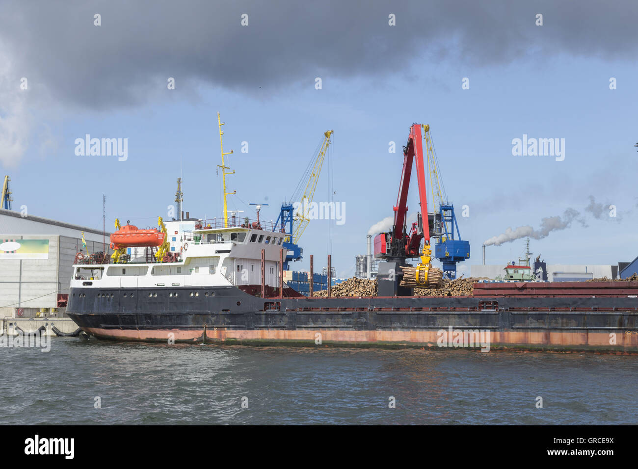 Nave da carico generale con il legname viene scaricata al porto di Wismar da escavatore Foto Stock