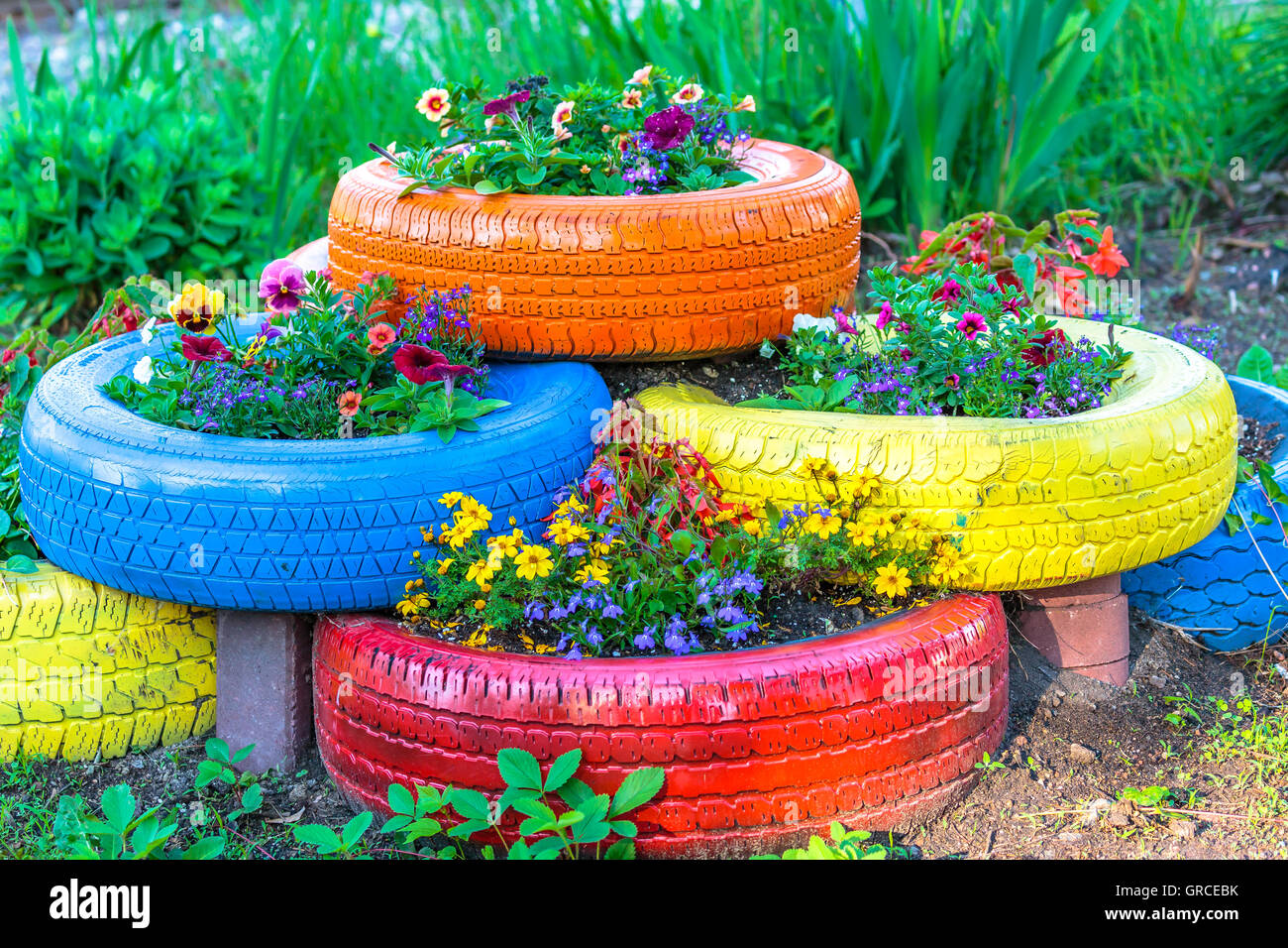 Vecchi pneumatici che sono dipinte in colori assortiti e utilizzato per un fiore della piantatrice. Foto Stock