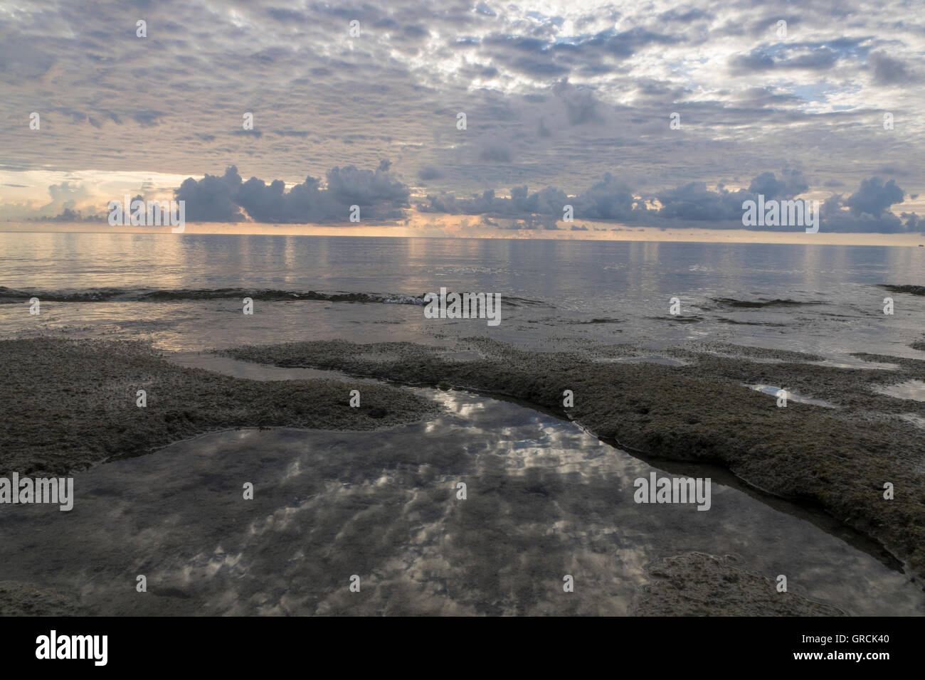 Alba in spiaggia durante la bassa marea, il mare piatto, Cumulus nubi Foto Stock