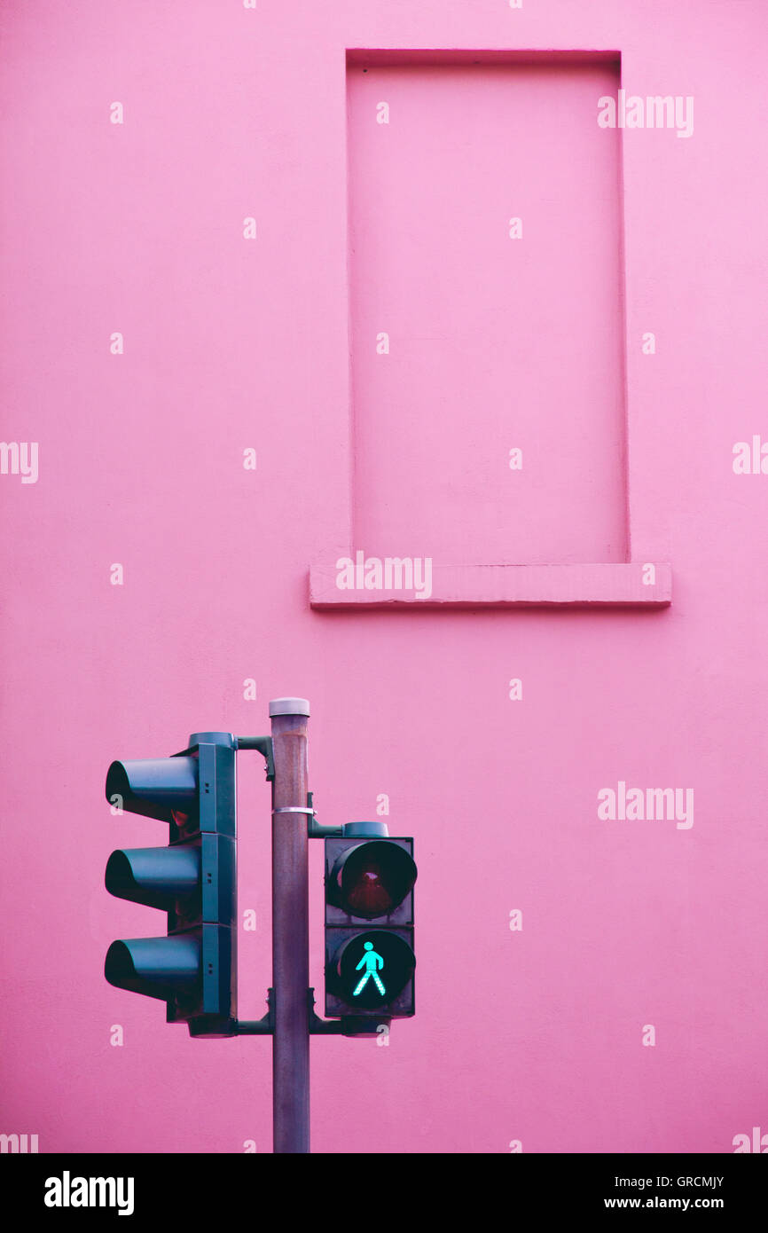 Il semaforo verde davanti casa rosa parete Foto Stock