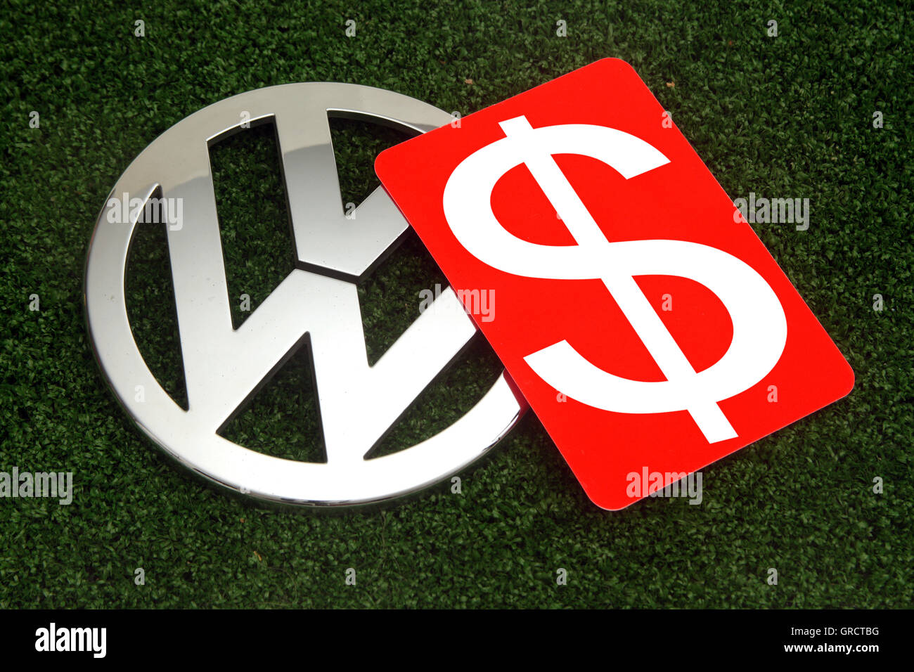 Us Dollar simbolo sulla scheda rossa con Vw segno sul tappeto erboso verde Foto Stock