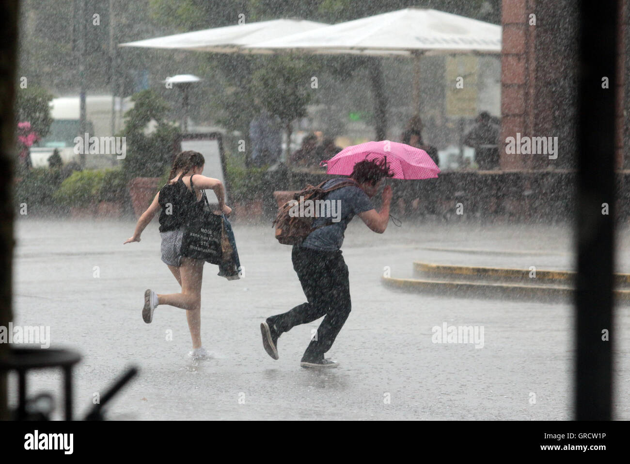 Giovane con ombrello scappando dalla pioggia pesante Foto Stock