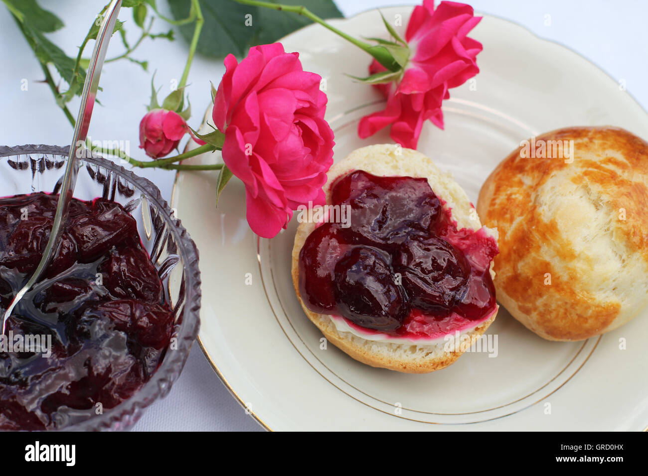 La prima colazione con pane appena sfornato focaccine fatte in casa e in casa Confettura di ciliegie Foto Stock