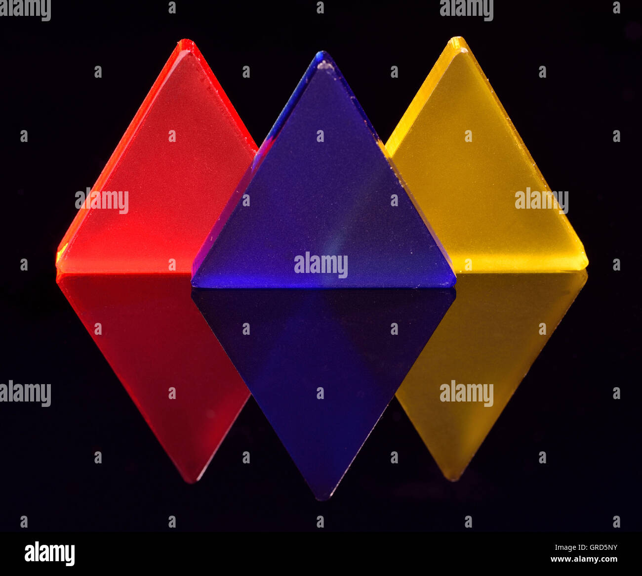 Triangels di rosso, blu e giallo con vetro acrilico con la riflessione su sfondo nero Foto Stock
