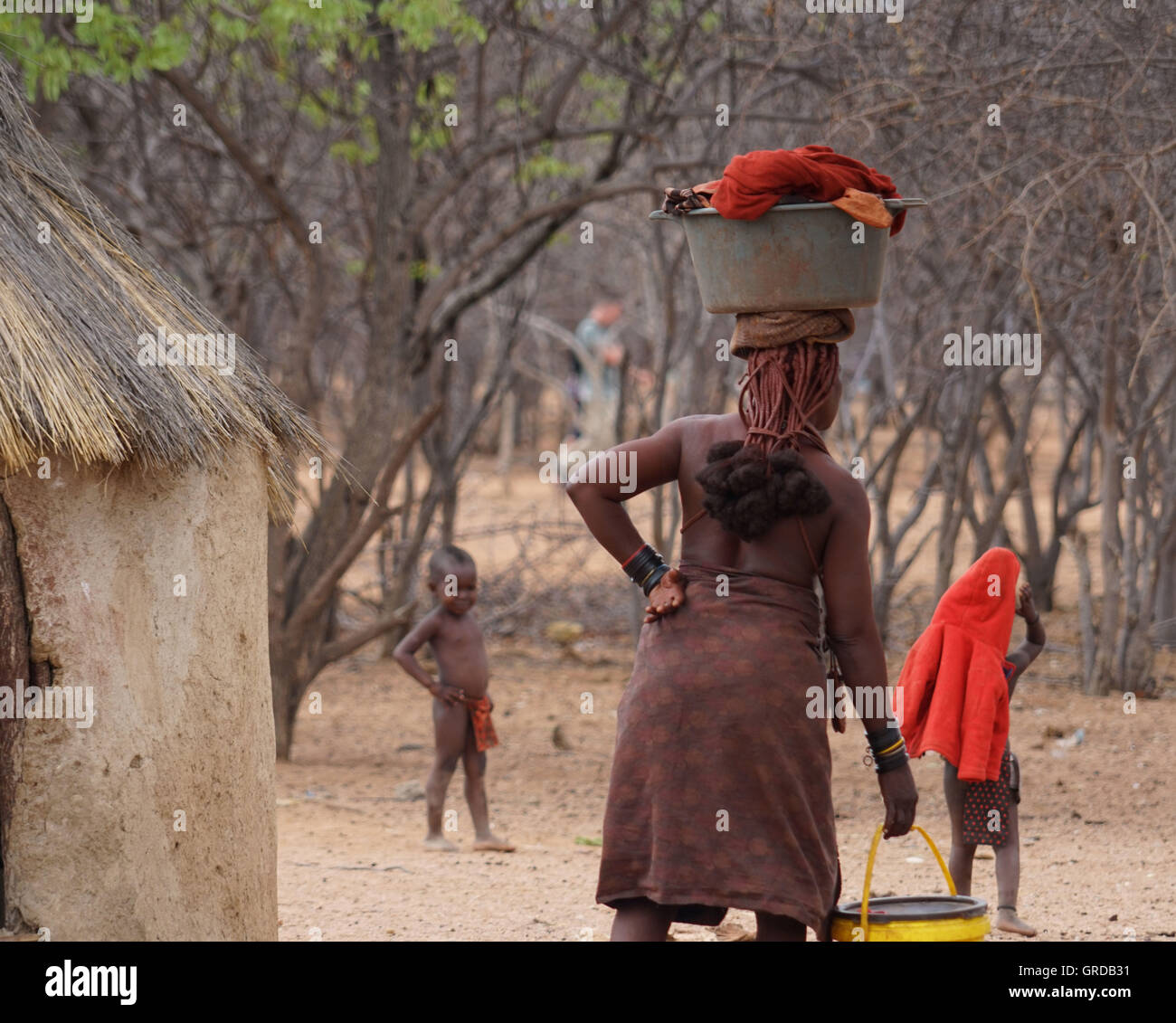 Himba donna che trasportano il secchio con lavanderia sul suo capo, Namibia Foto Stock