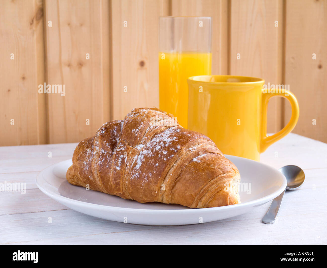 La prima colazione continentale brioche, caffè nella tazza di colore giallo e succo di arancia sul bianco tavolo in legno Foto Stock