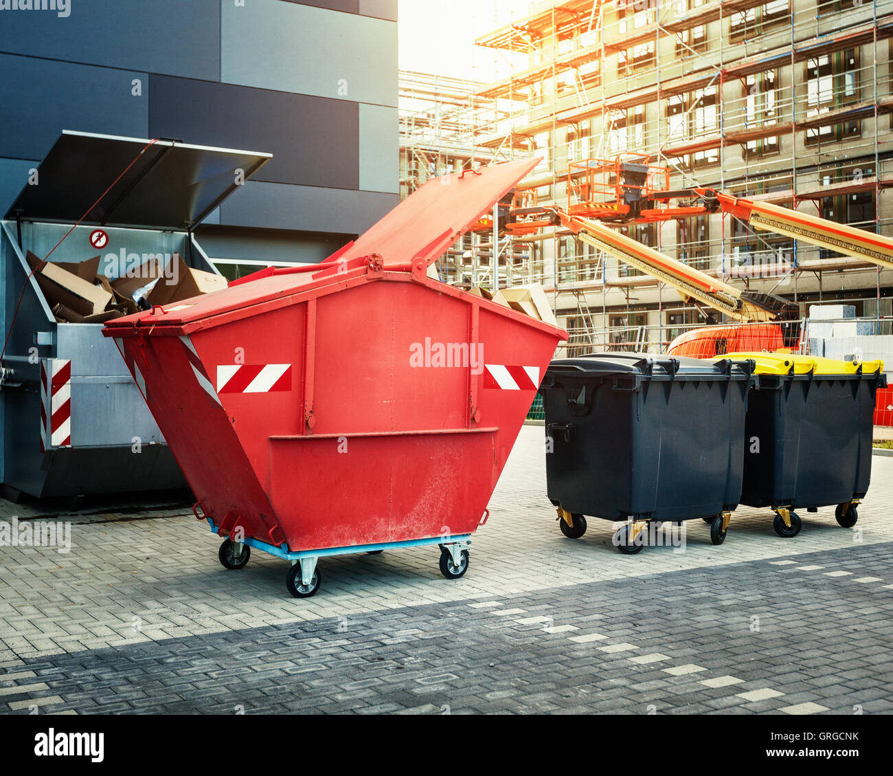 Dumpster rosso, il riciclaggio dei rifiuti e cassonetti vicino al nuovo edificio per uffici. Sito in costruzione sullo sfondo Foto Stock