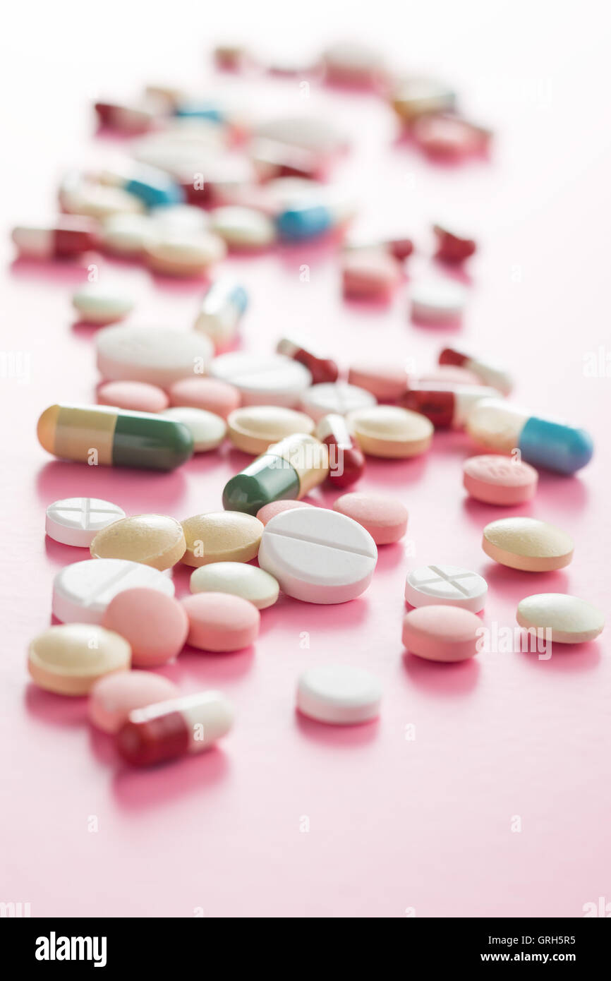 Le diverse pillole su sfondo rosa. Foto Stock