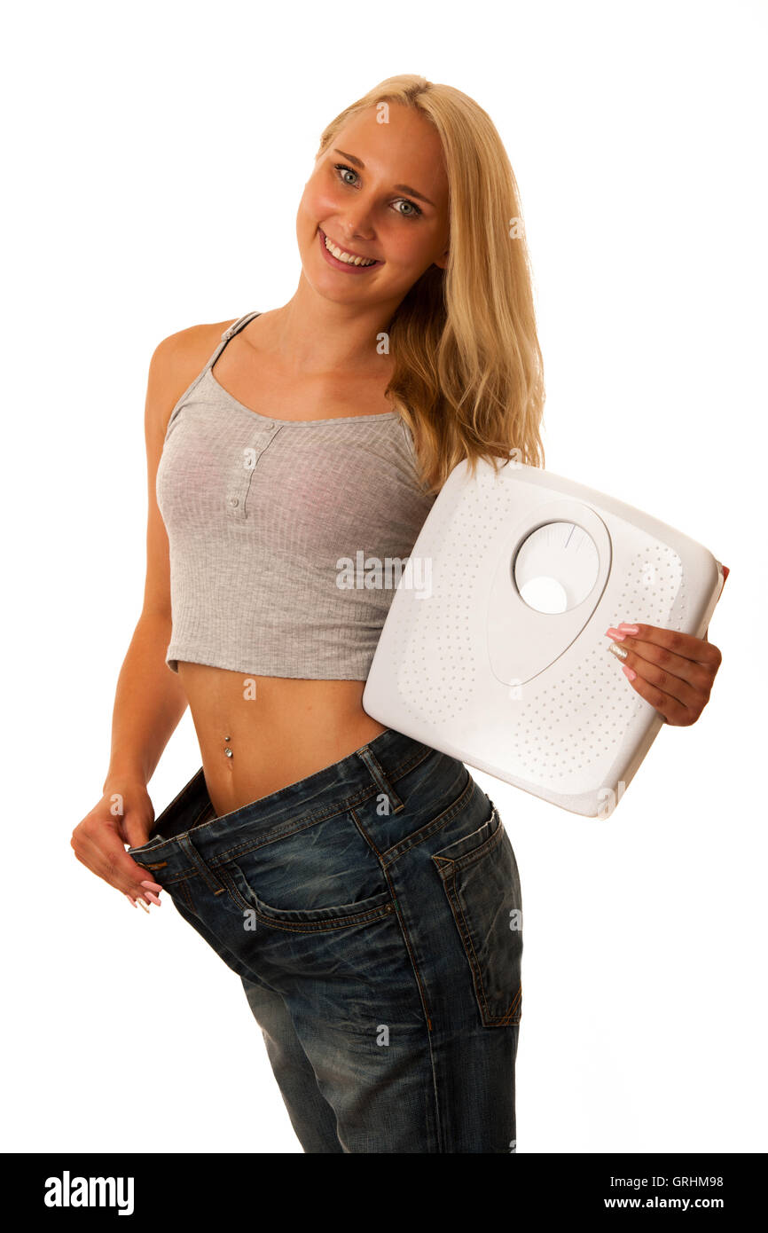 Uno stile di vita sano - montare una donna bionda con troppo grande pantaloni gesticolando peso allentato Foto Stock