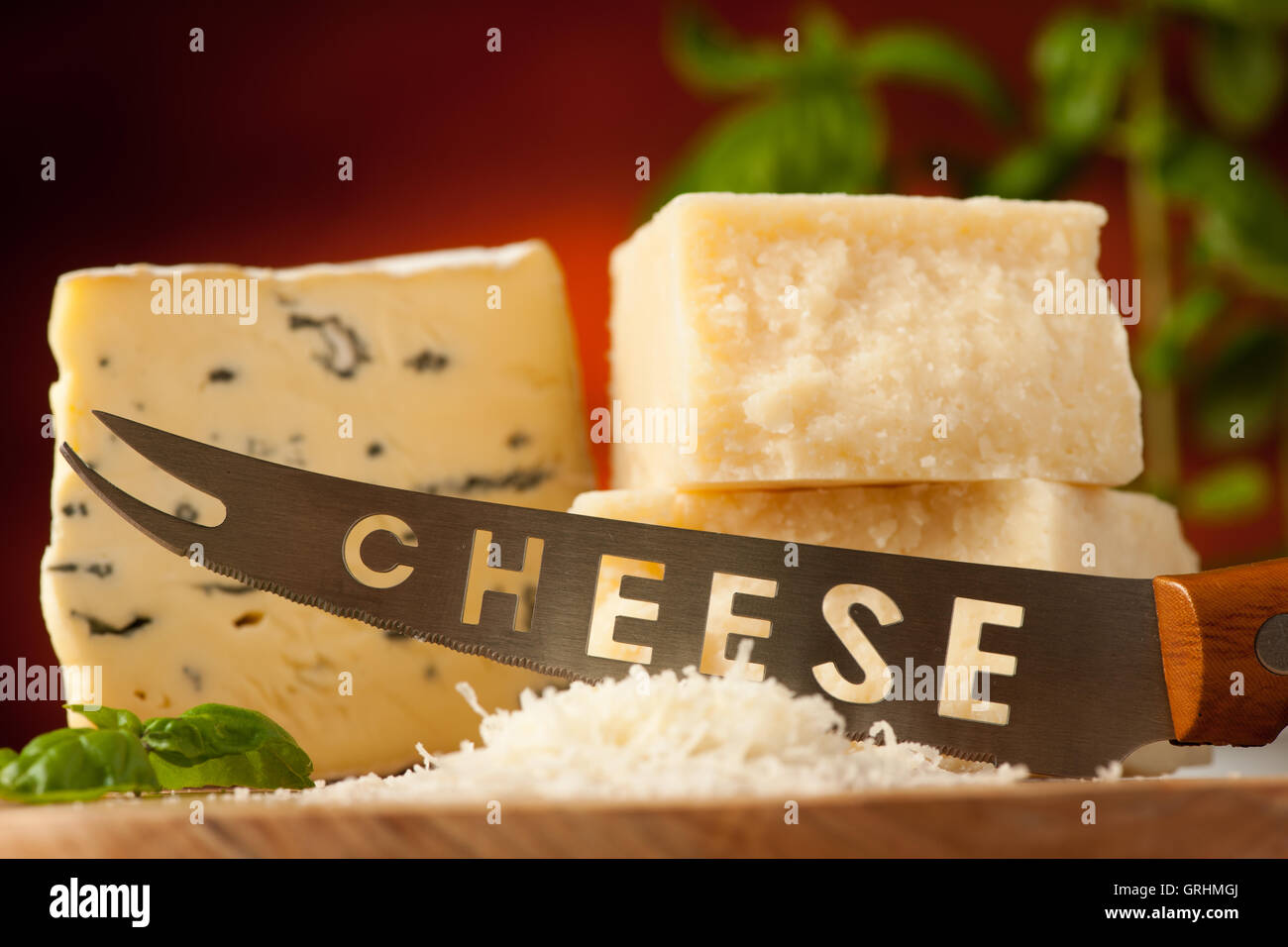 Pezzi di formaggio blu e parmigiano su un tagliere di legno essendo  tagliato con Coltello per formaggio con spezie su un ristorante in legno  Foto stock - Alamy