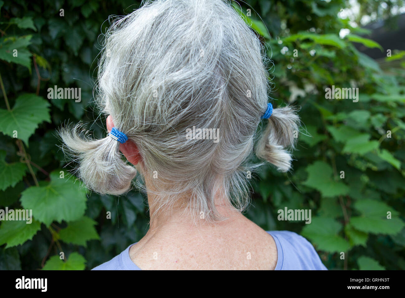 Donna con capelli grigi in pigtail Foto Stock