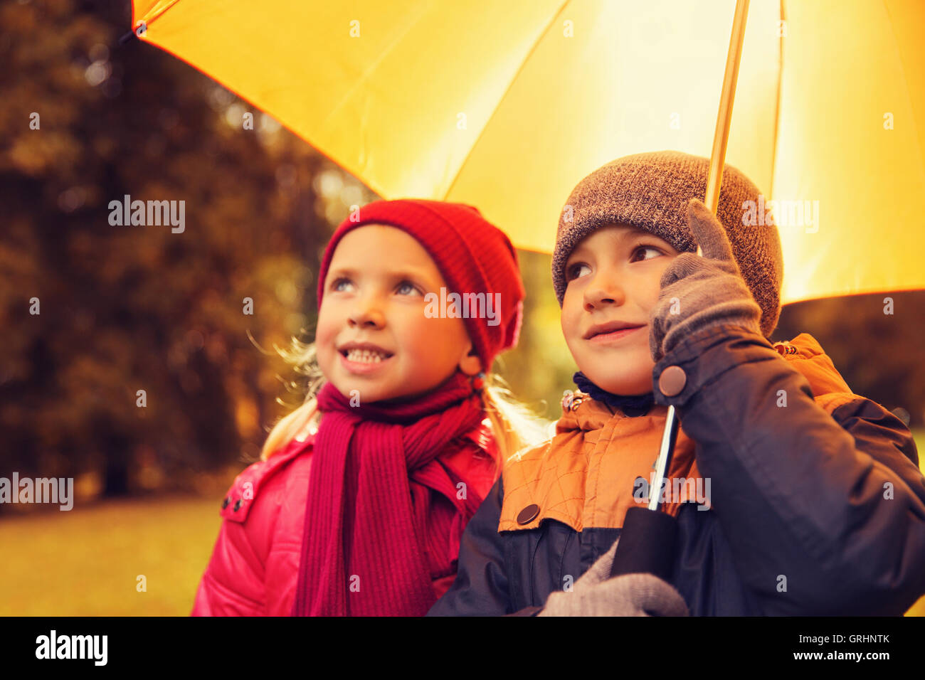 Felice un ragazzo e una ragazza con ombrello in autunno park Foto Stock