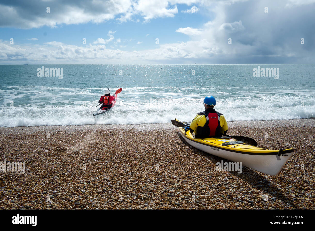 2 canoisti in canoa, uno in canoa sulla spiaggia in mare, mare blu cielo blu. Foto Stock