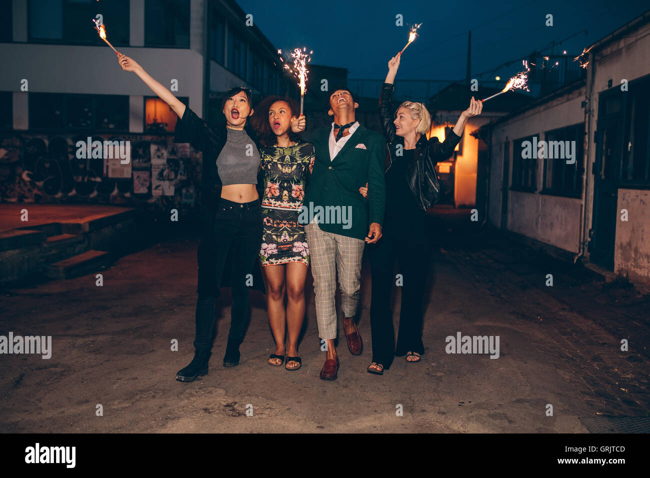 Gruppo di amici godendo con botti sulla strada della citta'. Giovani uomini e donne godendo il capodanno sulla strada con fuochi d'artificio. Foto Stock