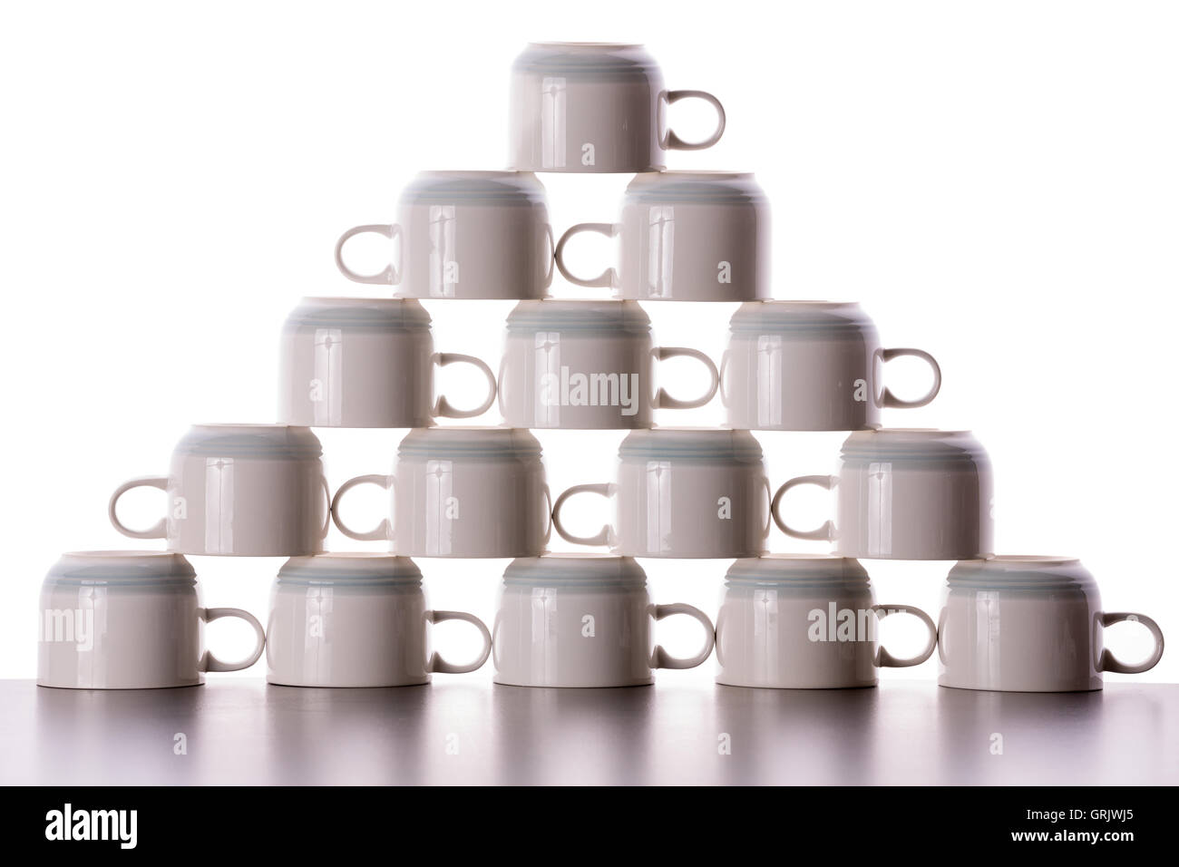 Attentamente piramide impilati di essiccazione di tazze di caffè con le maniglie rivolte in direzioni opposte in righe alternate in un divertente Foto Stock