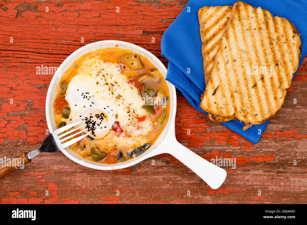 Giardino frittata servita con pane su un rosso rustico tavolo picnic con blue igienico e pane tostato Foto Stock