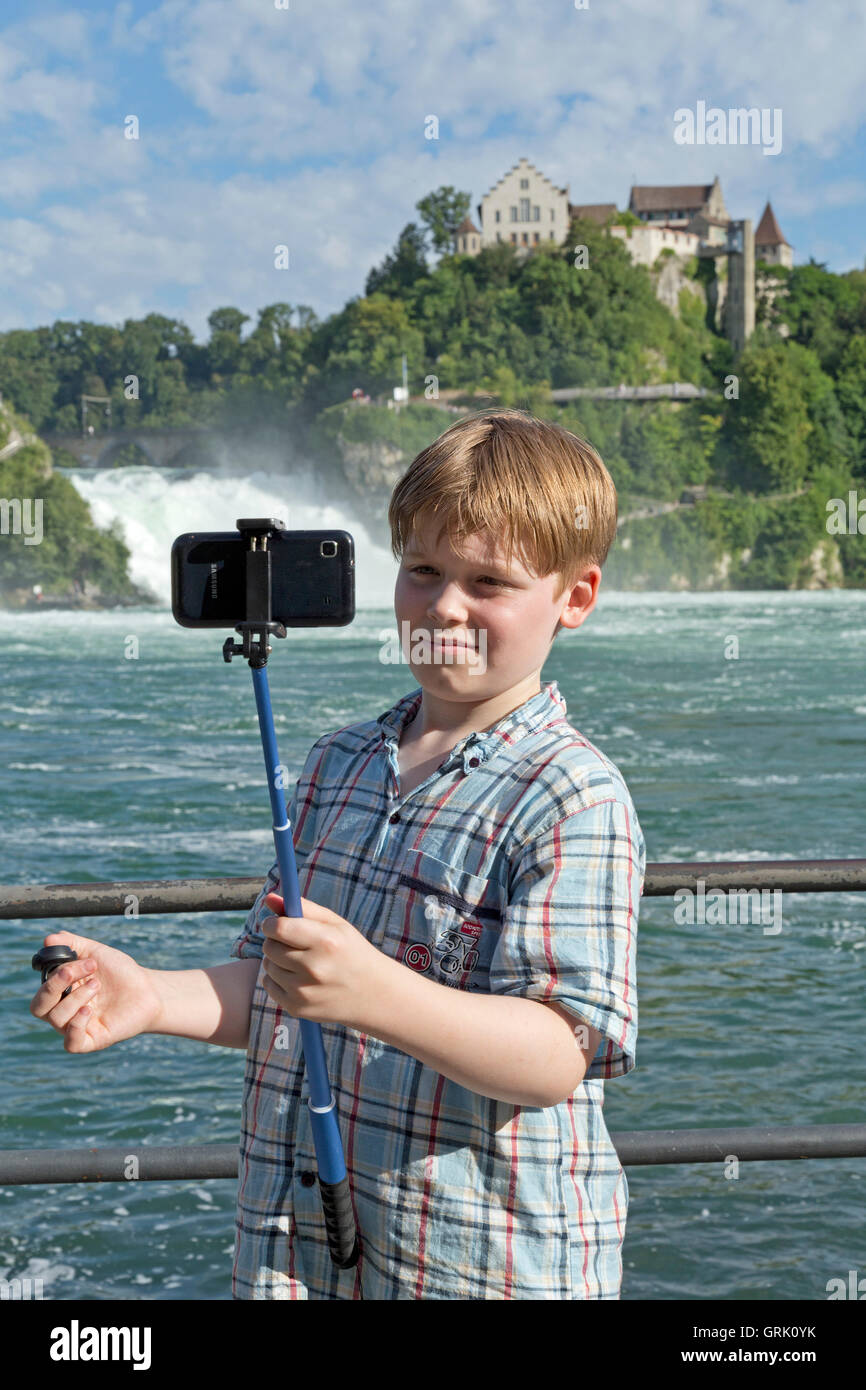 Ragazzo tenendo selfies, il fiume Reno Falls, Laufen Castello, Sciaffusa, Turgovia, Svizzera Foto Stock