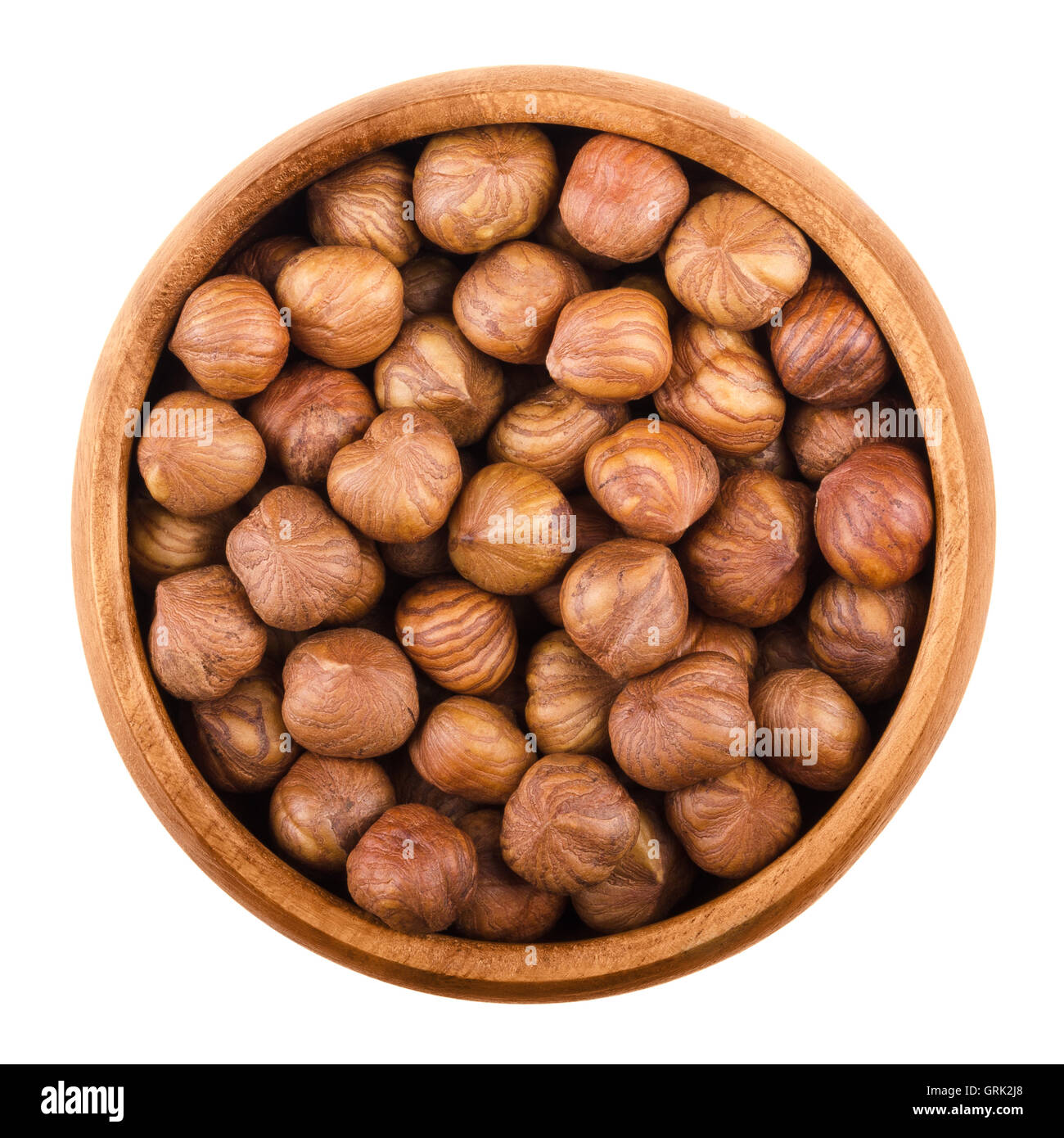 Le nocciole in una ciotola di legno su sfondo bianco. Sgusciate i semi maturi di una coltivate specie Corylus. Materie commestibili di frutta. Isolato Foto Stock