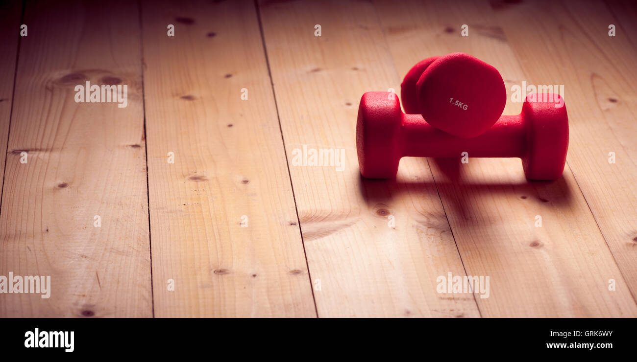 Luce rossa pesi su un pavimento di legno Foto Stock