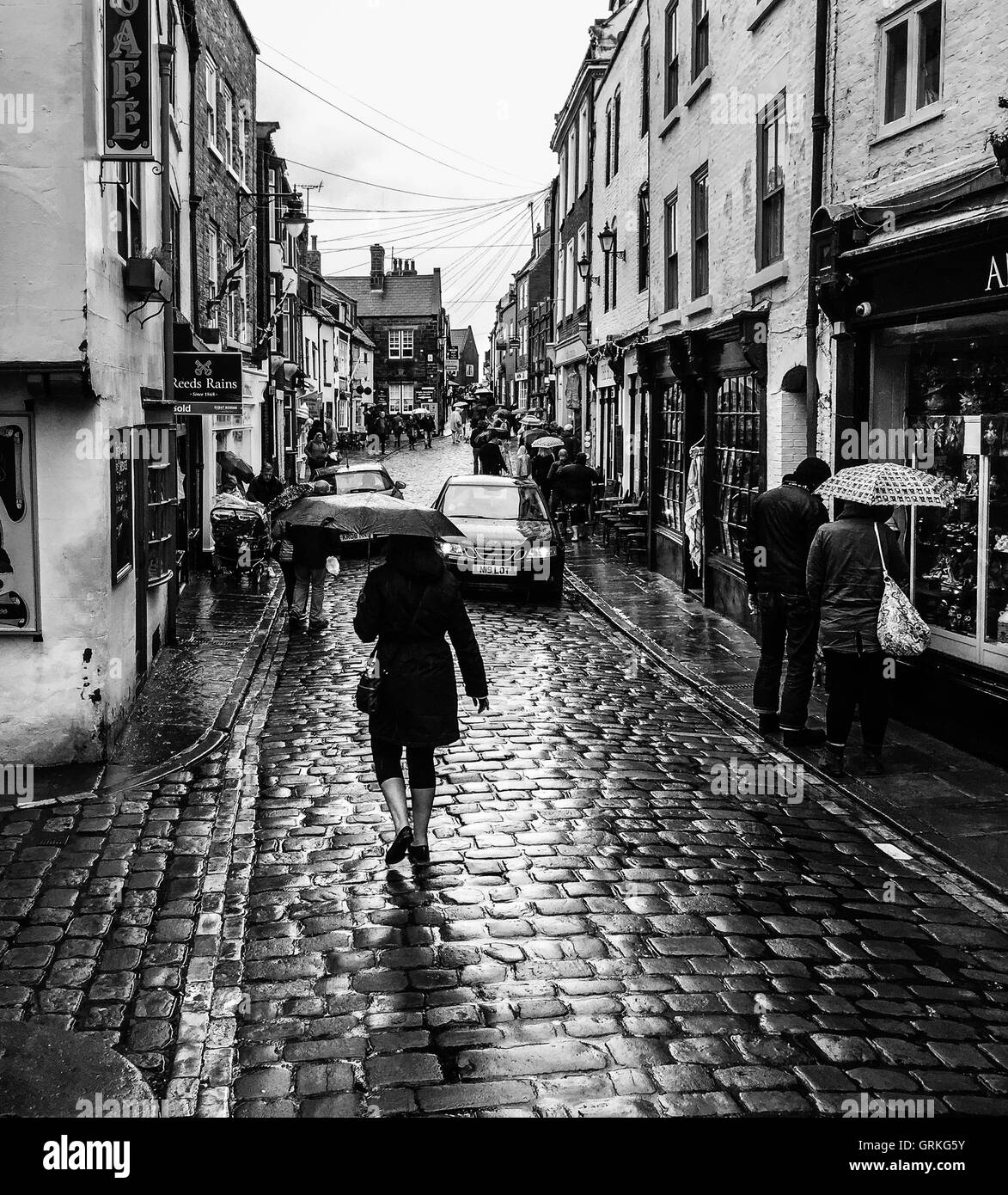 Varie persone su Church Street, sotto la pioggia. a Whitby, North Yorkshire, Inghilterra. Foto Stock