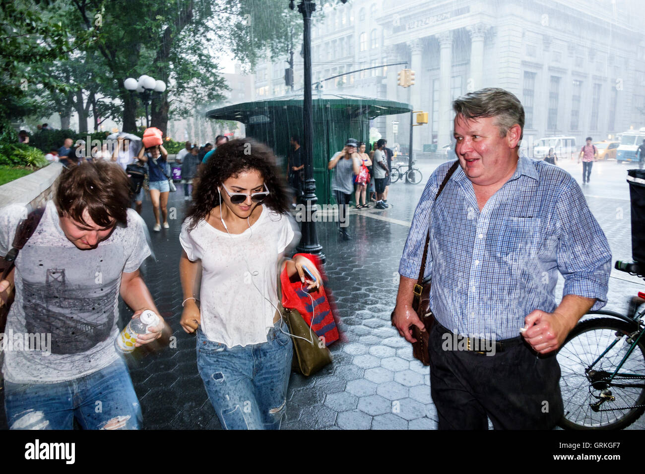 New York City,NY NYC,Manhattan,Midtown,Union Square,zona pedonale,strada trafficata,pioggia improvvisa,corsa,copertura,adulti,uomo uomo maschio,donna wome Foto Stock